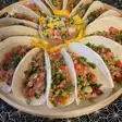 Taco cu carne tocată, roșii și ceapă verde, pe un platou rotund
