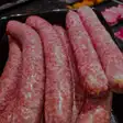 Cârnați proaspeți, groși și deschiși la culoare, în vitrină