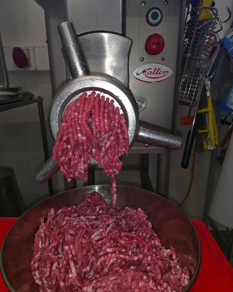 De vleesmolen in het atelier, gehakt komt eruit